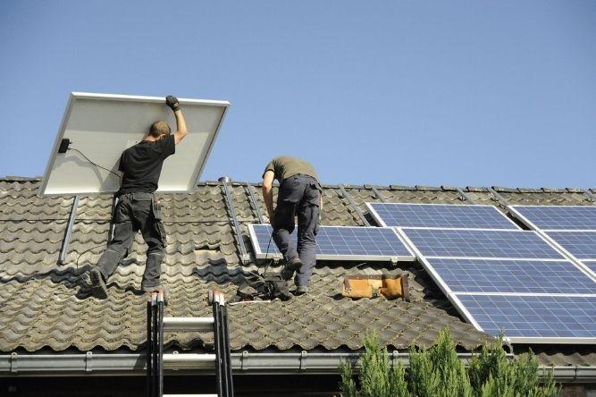 Workers on roof installing solar panels